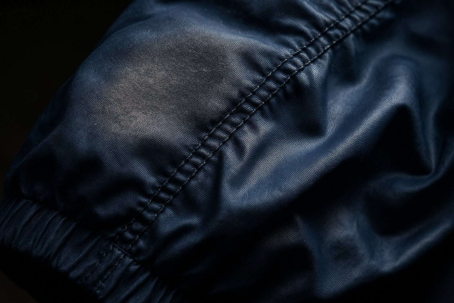 Macro shot of a polyester windbreaker sleeve showing a frosted matte patch, illustrating how to grade syn